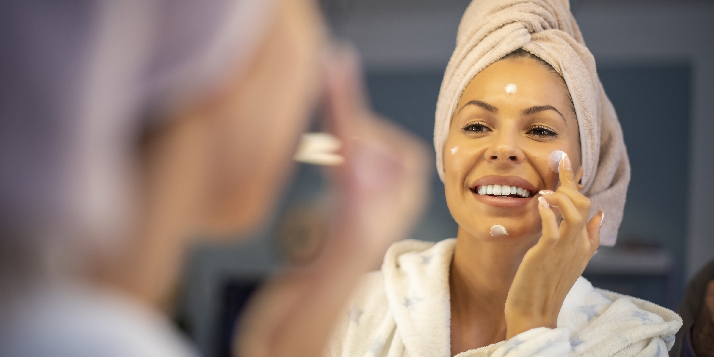 Young woman applying face cream.